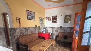 A room with a sofa, a wooden coffee table, a patterned wall, and a door with a window. - Omji Temple View Kharsali (Rajgarhi)