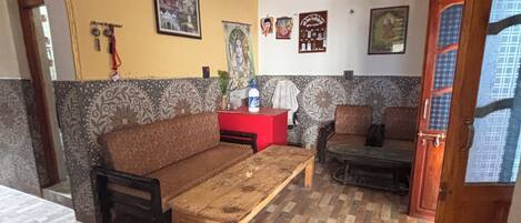 Una habitación con sofá, una mesa de centro de madera, pared decorada y una puerta con ventanal.
