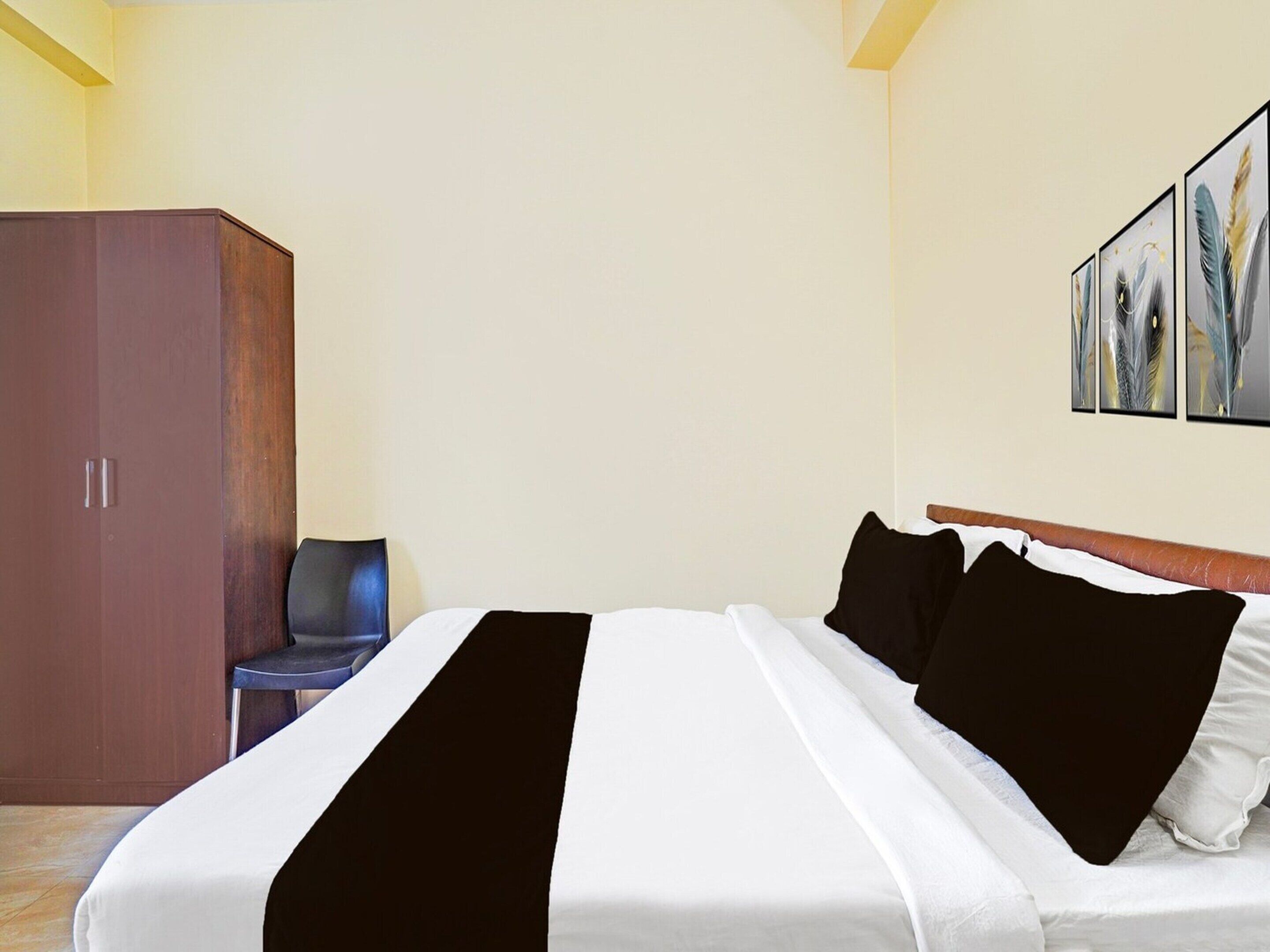 Een hotelkamer met een bed, een garderobe, een stoel en kunst aan de muur.