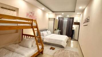 A bedroom with two beds, a wooden bunk bed, a bathroom with a mirror, and a tiled floor.