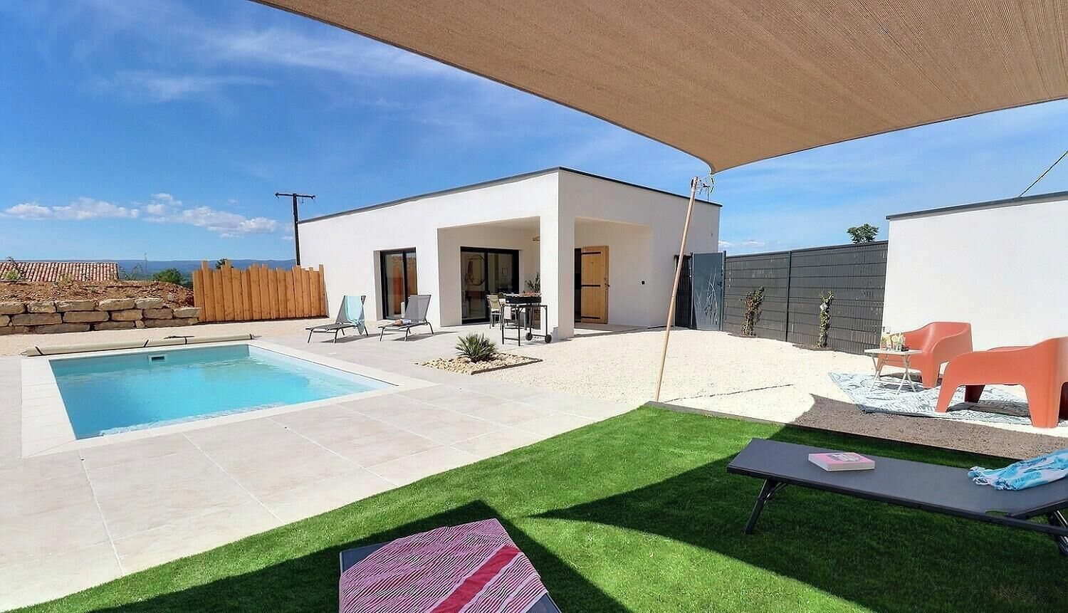 A modern outdoor pool area with a covered patio, a small garden, and a seating area.