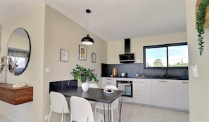A modern kitchen with a dining area, a large window, and a mirror. - NEW: The ultimate new villa with heated private pool, rated 4 stars (GROSPIERRES)