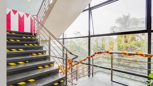 Eine Treppe mit Metallgeländern und gelben Sicherheitsmarkierungen, die zu einem Balkon mit Blick auf Grünflächen und Gebäude führt.