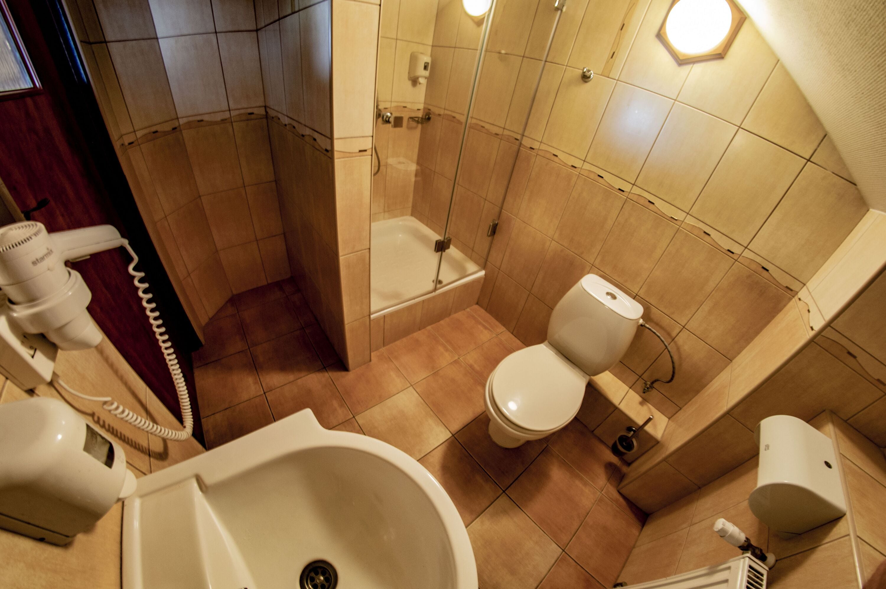 A bathroom with a bathtub, toilet, and a hand dryer.