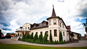 A large, multi-story building with a prominent tower, surrounded by well-maintained hedges. - Dworek Dębówko Jadwiga Jeżewicz (Bartoszyce)