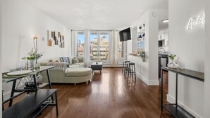 Una sala de estar moderna con sofá, mesa de comedor y zona de cocina.