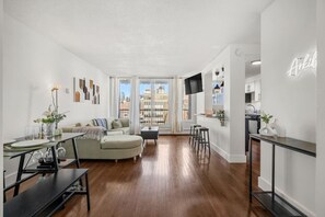 A modern living room with a sofa, dining table, and kitchen area. - Mins to Saddledome | UG Parking | 2 Bed | Central (Calgary)