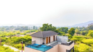 Ein modernes Haus mit Balkon, Schwimmbad und Blick auf die umliegende Natur und Hügel.