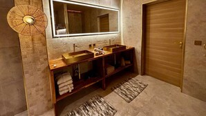 Une salle de bain moderne avec un grand miroir, deux vasques et un meuble-lavabo en bois.