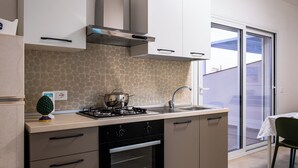 Une cuisine de taille réduite équipée d’une cuisinière à gaz, d’un four et d’un évier.