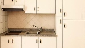 Een keuken met witte kasten, een roestvrijstalen spoelbak en een geïntegreerde afzuigkap.