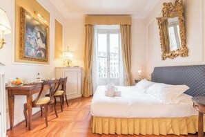A hotel room with a bed, a desk, chairs, a painting, a mirror, and a window with curtains. - Renaissance Elegance in the Heart of Florence (Firenze)