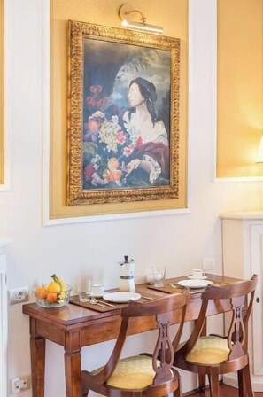 A dining area with a table set for four, a painting above the table, and a fruit bowl on the table. - Renaissance Elegance in the Heart of Florence (Firenze)