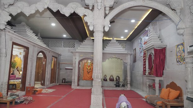 An ornate temple interior with a central deity, red carpet flooring, and traditional seating. - Omji Ashram Varanasi (Varanasi)