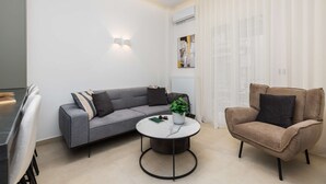 Una sala de estar moderna con un sofá gris, una mesa de centro redonda y un sillón marrón.