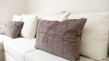A white sofa with several cushions, including a ribbed one and a plain one.