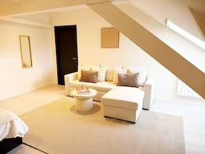 A modern living room with a white sofa, a round coffee table, and a large window.