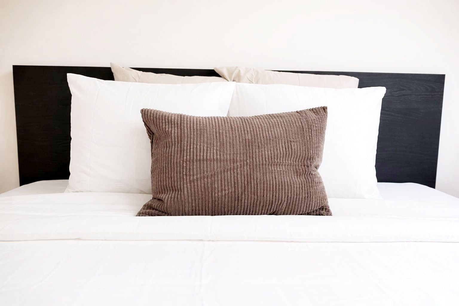 A bed with a white mattress, a black headboard, and two pillows.