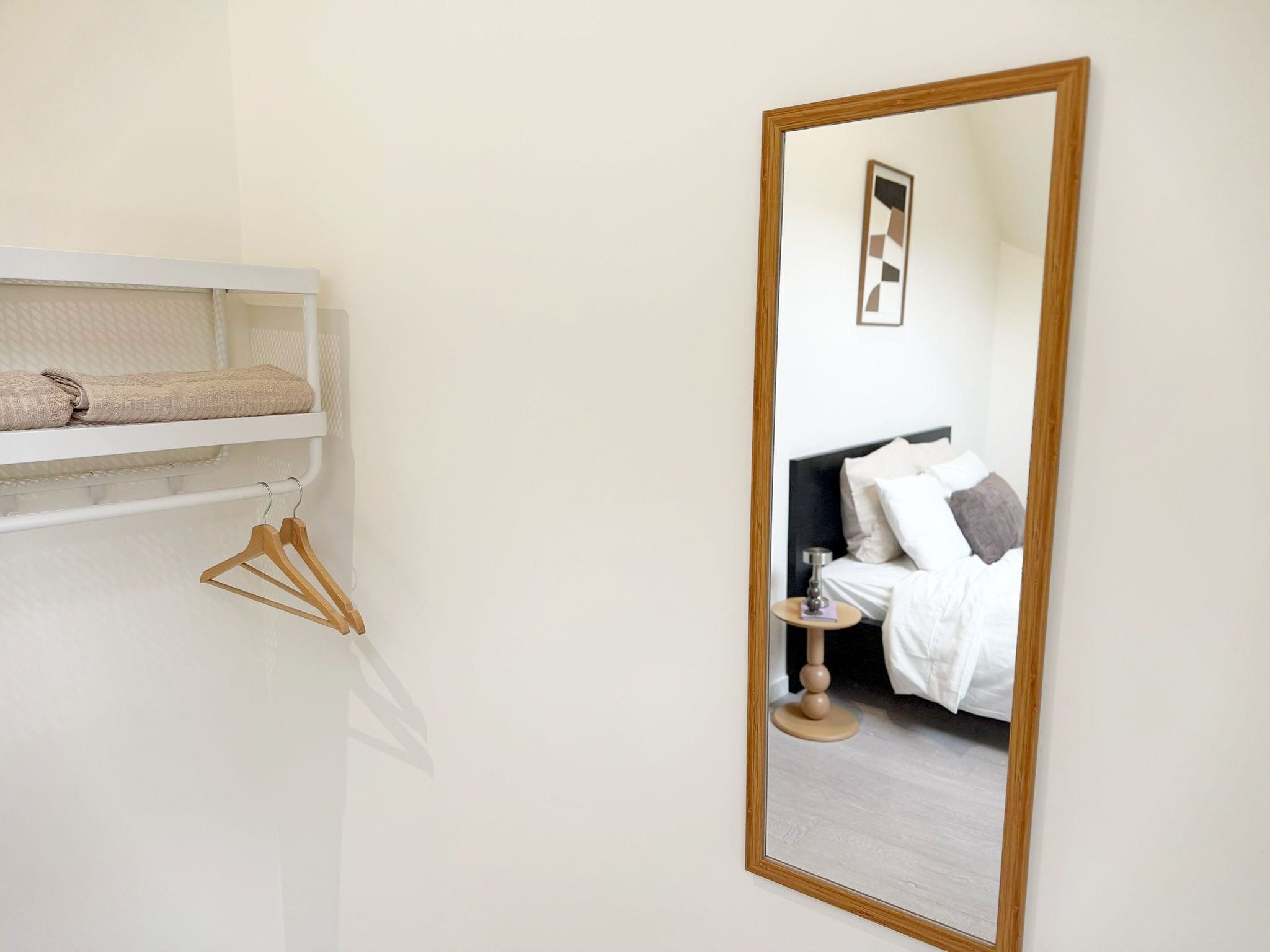 Una camera d'albergo con un letto, un comodino e uno specchio.