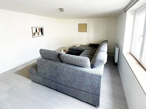 Una sala de estar moderna con un sofá gris, una mesita con un hervidor y un radiador.