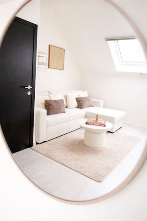 A modern living room with a white sofa, a coffee table, and a black door.
