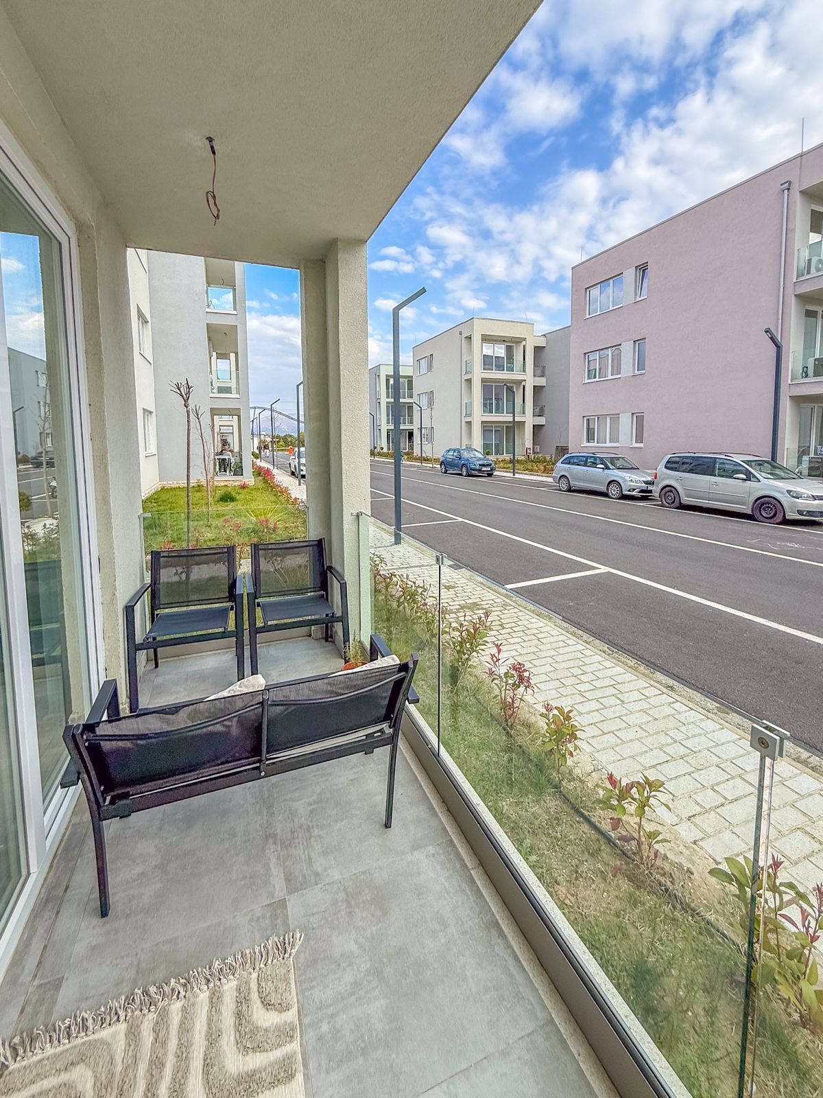 A balcony with a bench, a view of a road, and modern buildings in the background.