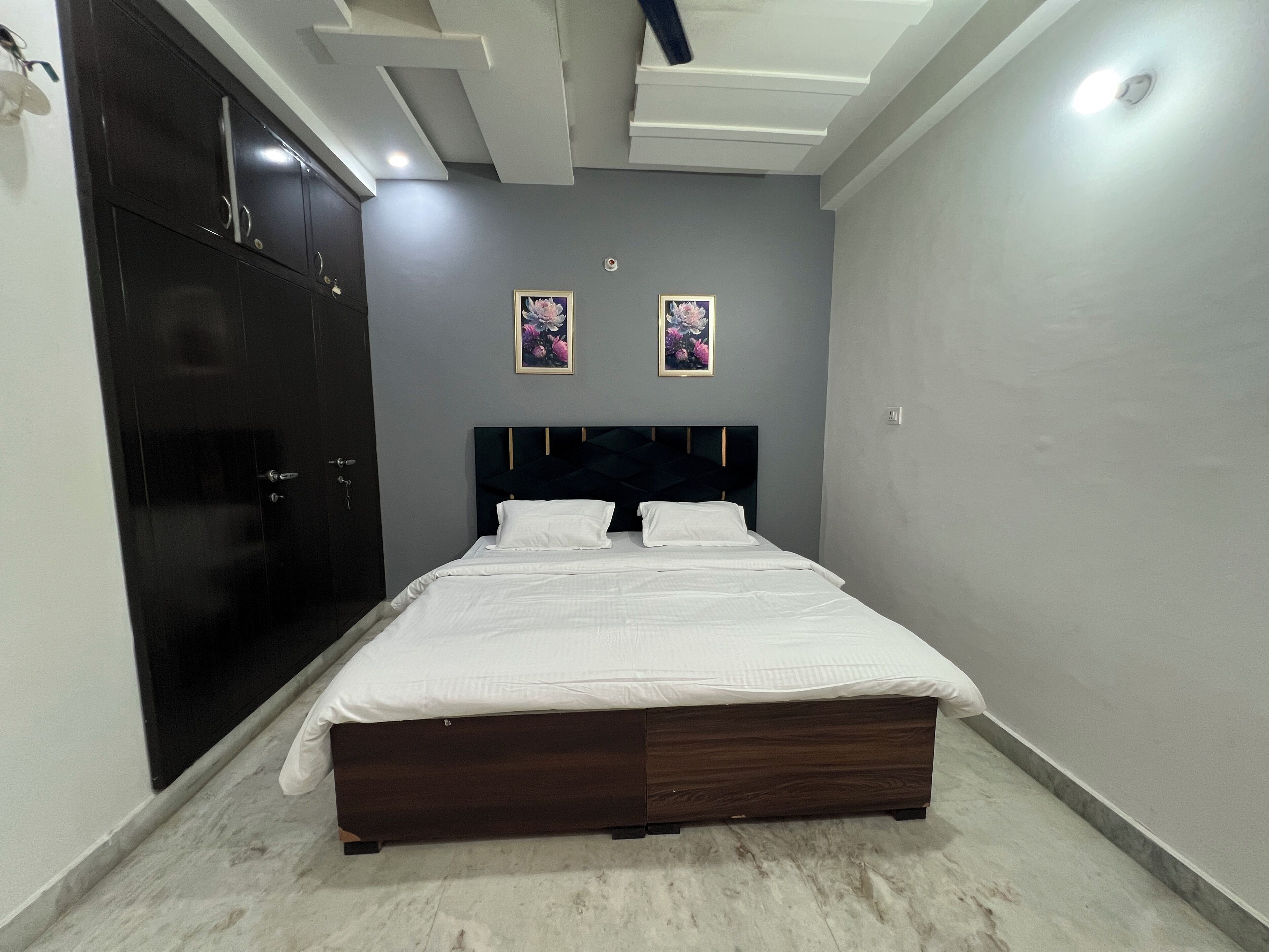 A bedroom with a bed, wardrobe, and two wall-mounted flower pictures.