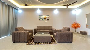 Un salon moderne comprenant un ensemble de canapés, une table basse, un tapis à motifs de girafe, des ventilateurs de plafond, un éclairage encastré et un tableau accroché au mur.