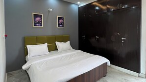 Une chambre à coucher comprenant un lit, un ventilateur de plafond, des spots encastrés, une armoire et deux tableaux encadrés accrochés au mur.