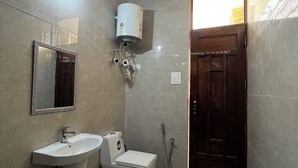 Une salle de bain équipée d’un lavabo sur colonne, de toilettes, d’une douche et d’un miroir.
