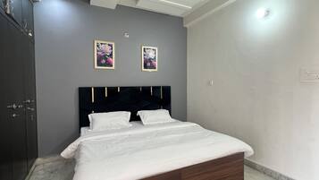 Ein Schlafzimmer mit einem Bett, einem Deckenventilator, eingelassener Beleuchtung und zwei gerahmten Blumenbildern an der Wand.