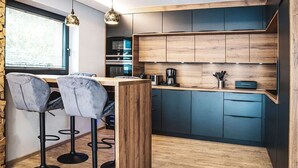 Une cuisine moderne avec des meubles en bois, un coin bar avec des tabourets et des luminaires suspendus.
