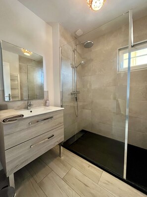 Une salle de bain moderne avec une douche à parois de verre, un meuble-lavabo avec un miroir et un évier.