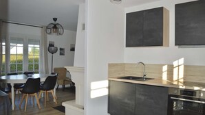 Eine moderne Küche mit integriertem Geschirrspüler, Spüle und Herd. Ein Essbereich mit Tisch und Stühlen ist ebenfalls vorhanden.