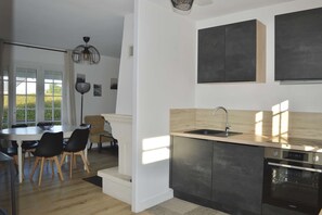 Eine moderne Küche mit integriertem Geschirrspüler, Spüle und Herd. Ein Essbereich mit Tisch und Stühlen ist ebenfalls vorhanden.