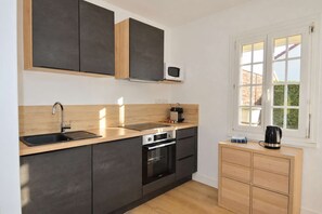 Eine moderne Küche mit integriertem Backofen, Mikrowelle und Kaffeemaschine auf der Arbeitsplatte.