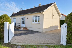 Ein eingeschossiges Haus mit geschlossenem Eingangstor, einer Garage und einer kurzen Auffahrt.
