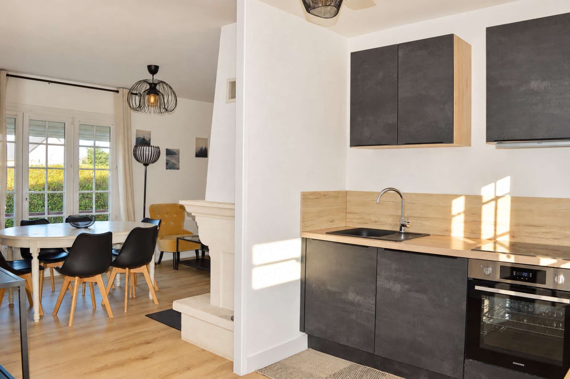 Een moderne keuken met een inbouwoven, een spoelbak en een eethoek met stoelen en een tafel.