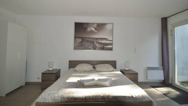 Una camera da letto con un letto, un comodino, una finestra e un quadro appeso al muro.