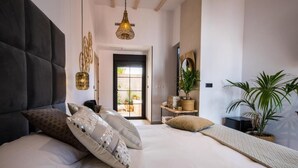 A bedroom with a large bed, a hanging light fixture, a potted plant, and a view of the outdoors. - La Posada de Consuelito (Chiloeches)