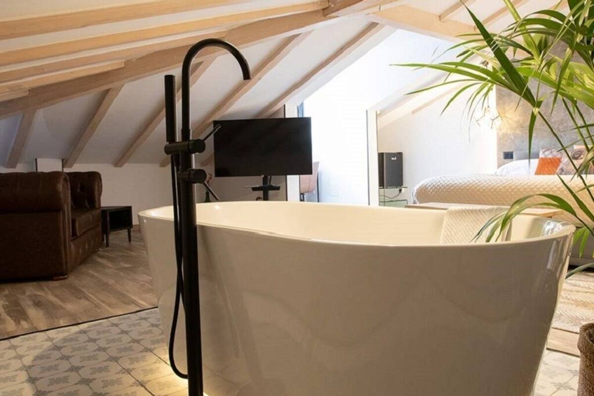 A modern bathroom with a freestanding bathtub, a black floor lamp, and a potted plant.