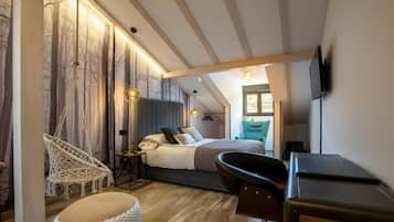 Ein modernes Schlafzimmer mit Bett, Schreibtisch, Stuhl, einer Pendelleuchte und einem an der Wand montierten Fernseher.