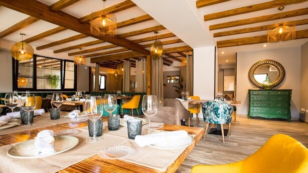 A dining area with wooden tables, yellow chairs, and a green dresser. - La Posada de Consuelito (Chiloeches)