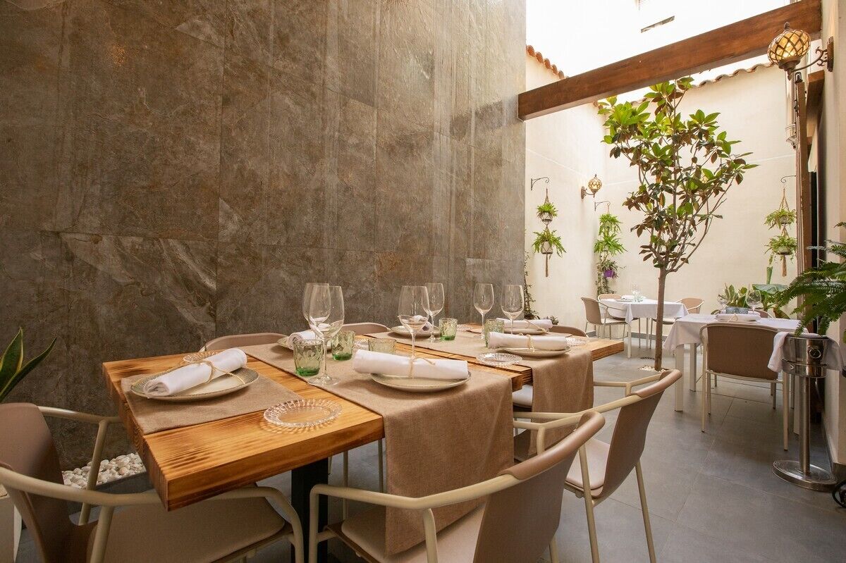 A dining area with tables set for two, each with a plate, glass, and napkin.
