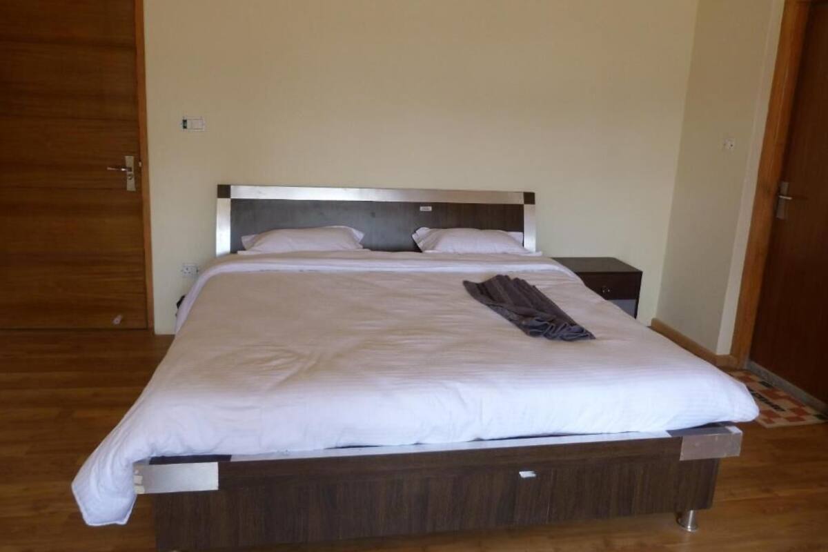 A neatly made bed with a wooden headboard, a bedside table, and a door to the left.
