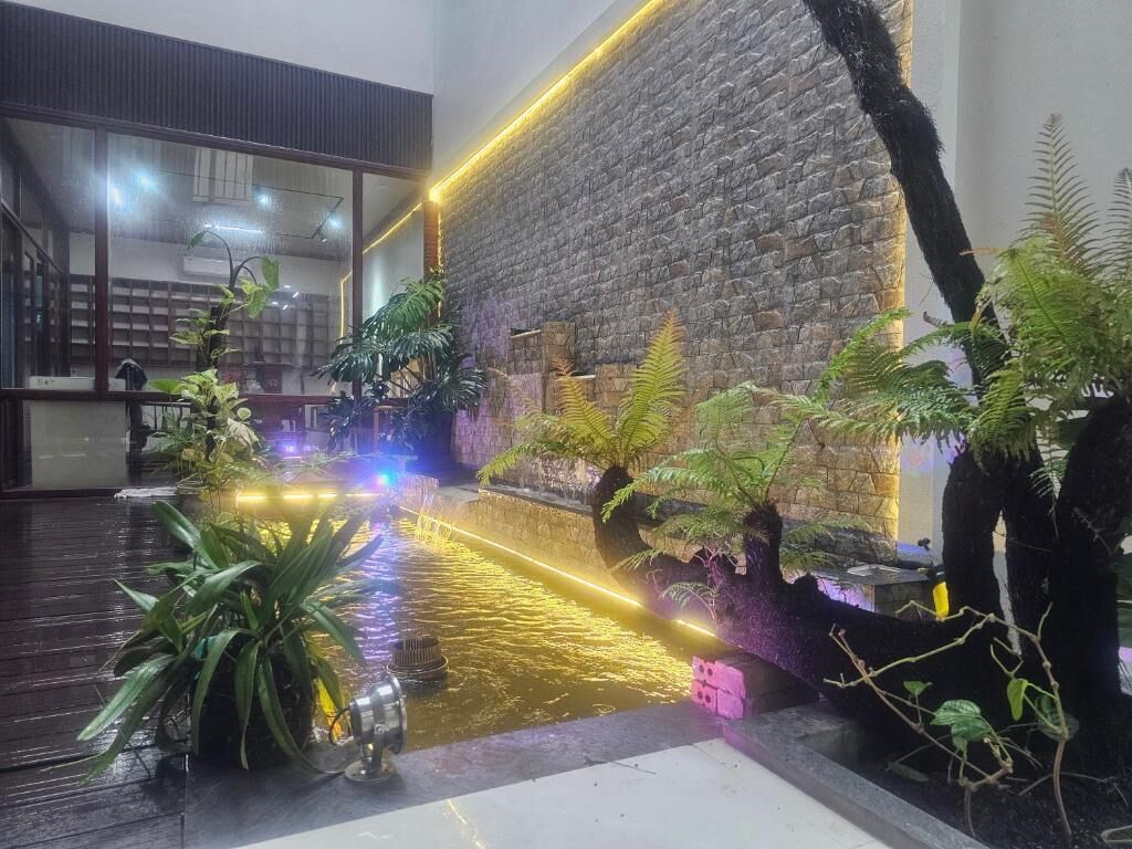An indoor space with a water feature, plants, and a brick wall.