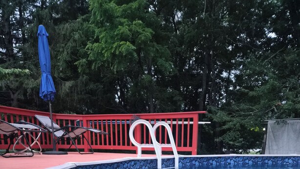 A swimming pool with a red deck, a white ladder, and lounge chairs. - HIdden Gem (Wallkill)