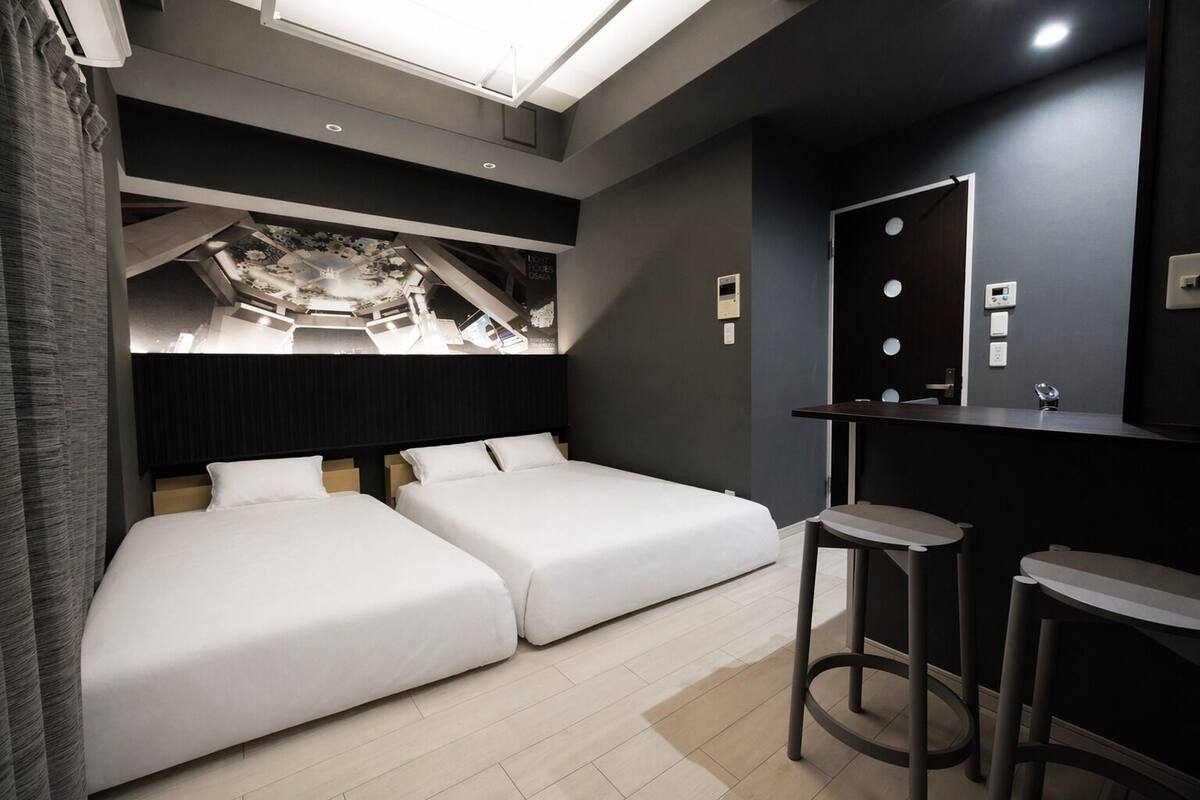 Una habitación de hotel moderna con dos camas, un escritorio y un espejo.