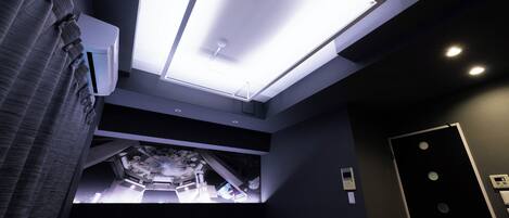 Una habitación de hotel moderna con tragaluz, una cama, una mesita de noche y un equipo de aire acondicionado de pared.