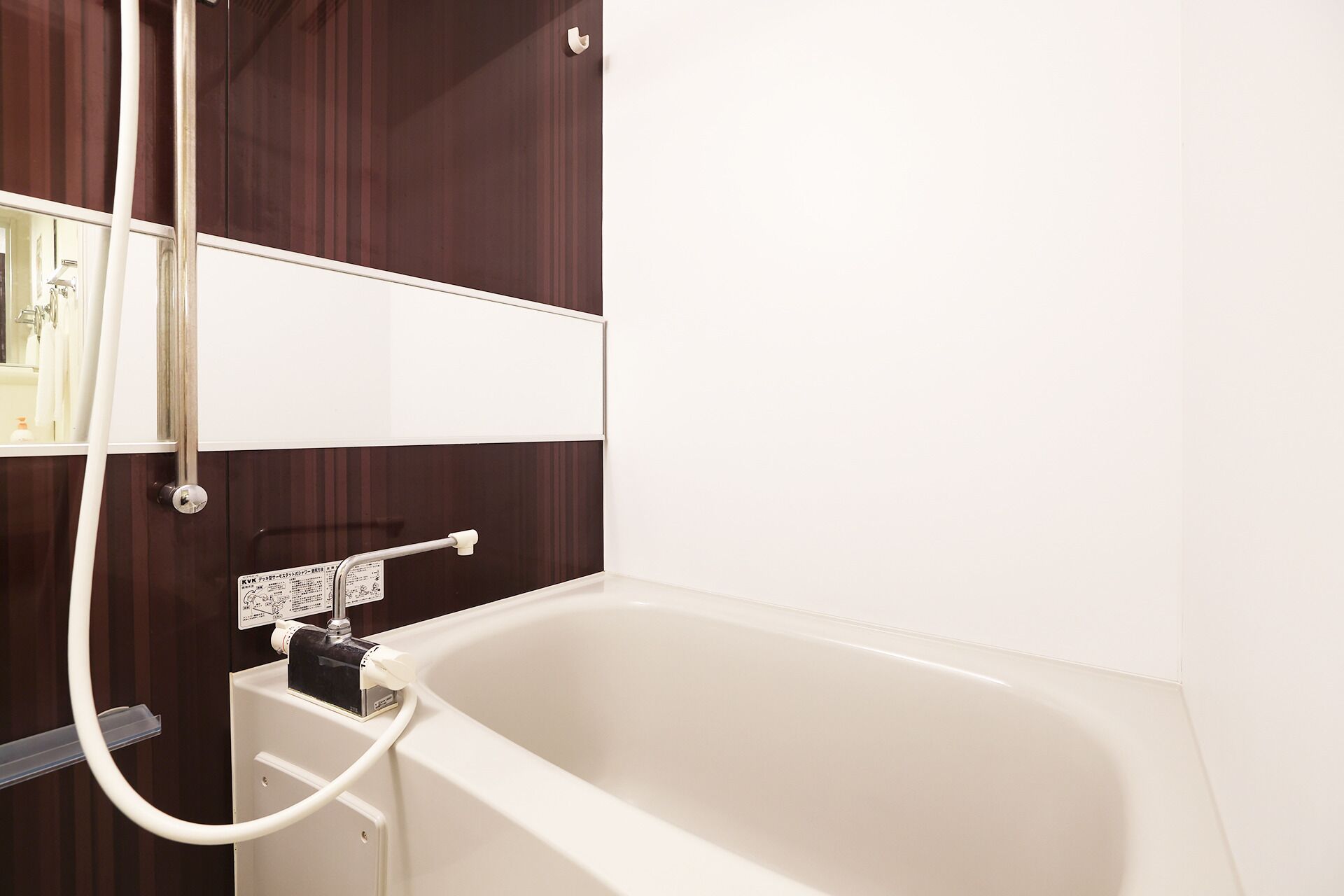 Une salle de bain avec une baignoire, une douchette et un miroir.